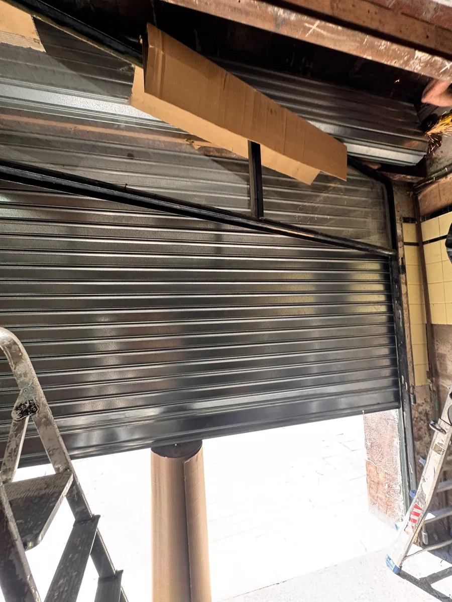 Montaje de persiana metálica y eje en un local comercial en obras