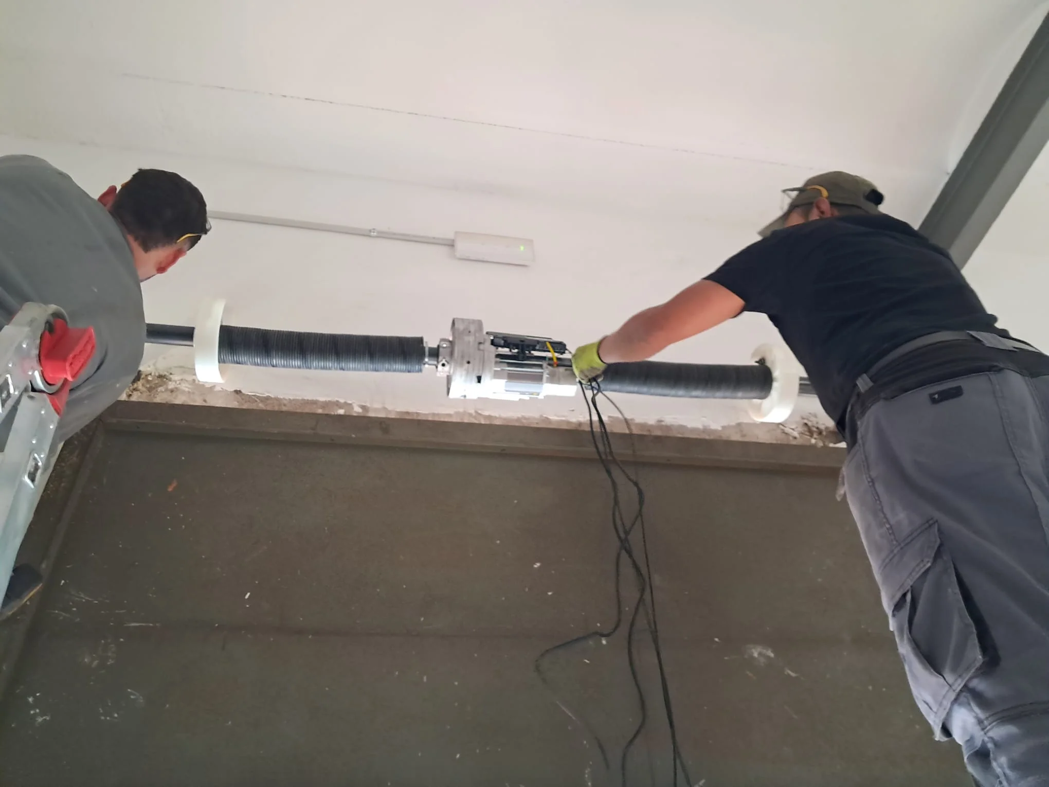 Montaje del eje de una persiana metálica en un local comercial