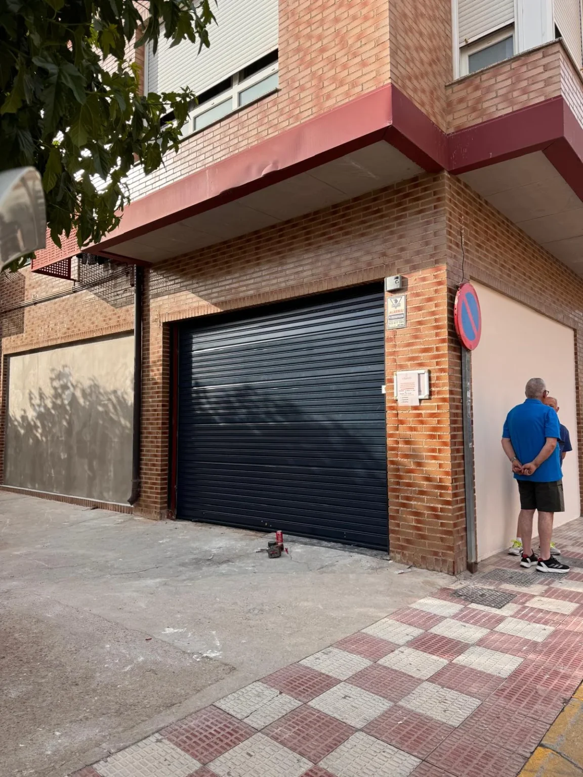 Entrada con puerta enrollable de piedra y acceso estrecho.