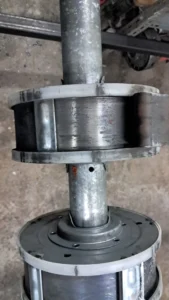 mantenimiento de persianas metalicas - Eje metálico con dos rodillos plásticos montados, con óxido y desgaste visible.