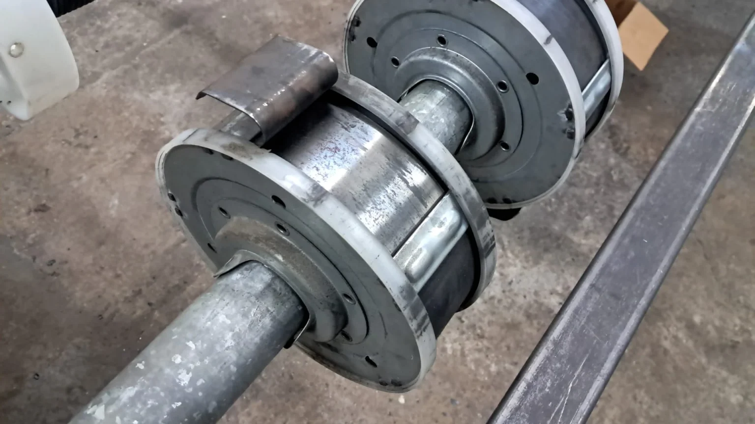 Conjunto de rodillos industriales metálicos montados en un eje, con desgaste visible.