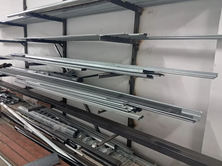 Estantería de pared con perfiles y barras metálicas apiladas y organizadas en un taller.