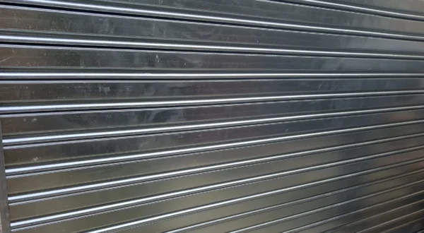 Persiana metálica enrollable de seguridad cerrada con candado en la entrada de un almacén.