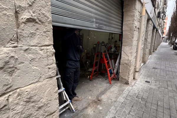 Técnicos de Accesos Nordeste realizando la instalación de una persiana metálica enrollable en un comercio de Barcelona.