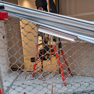 Operario instalando una persiana metálica de panal o biela con escalera en local comercial de Barcelona.
