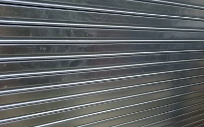 Persiana metálica enrollable cerrada con candado en la parte inferior y entorno de almacén. Tipos de lamas. Blogs